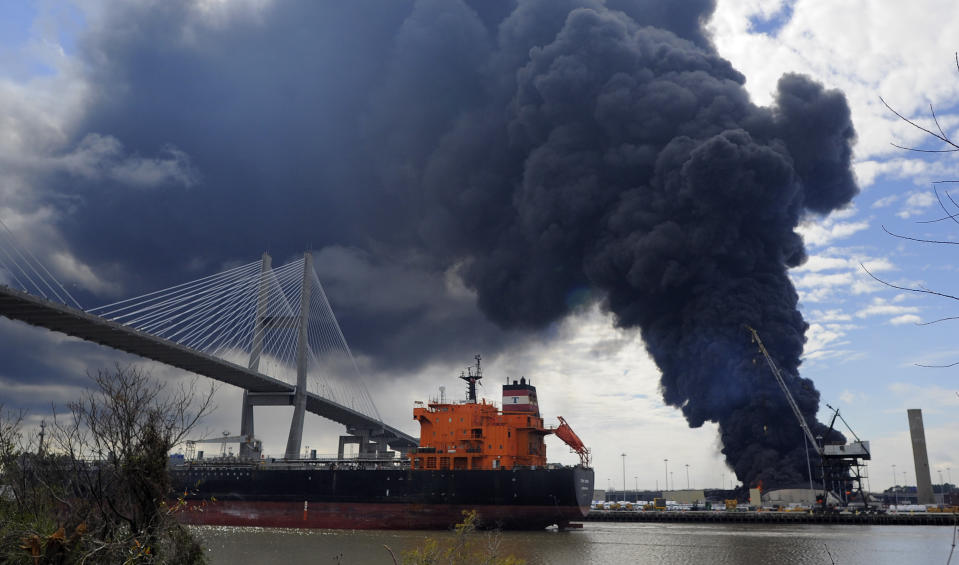 A tanker sails past a warehouse fire at the Georgia Ports Authority Ocean Terminal that Savannah firefighters are battling to contain, Saturday, Feb. 8, 2014, in Savannah, Ga. A Georgia Ports Authority spokesman said all port workers were safe and accounted for after the fire broke out. (AP Photo/Stephen B. Morton)