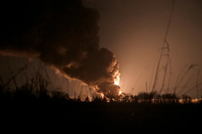 A plume of smoke and flames is seen in the distance.