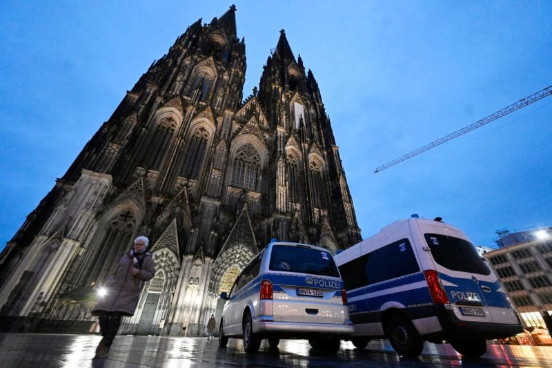 Police stand  at the entrance to Cologne Cathedral before the start of early mass on Christmas Day. Due to indications of a planned Islamist attack, the police have stepped up security measures. Roberto Pfeil/dpa