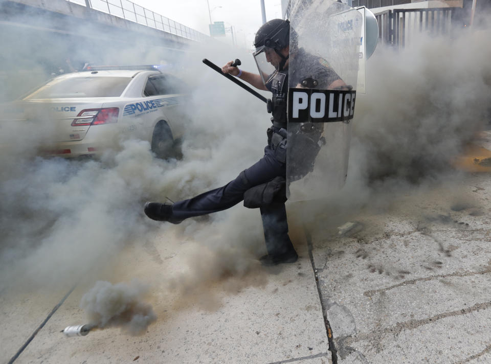 A policeman kicks back a tear gas canister during a demonstration next to the city of Miami Police Department, Saturday, May 30, 2020, downtown in Miami. Protests were held throughout the country over the death of George Floyd, a black man who died after being restrained by Minneapolis police officers on May 25.(AP Photo/Wilfredo Lee)