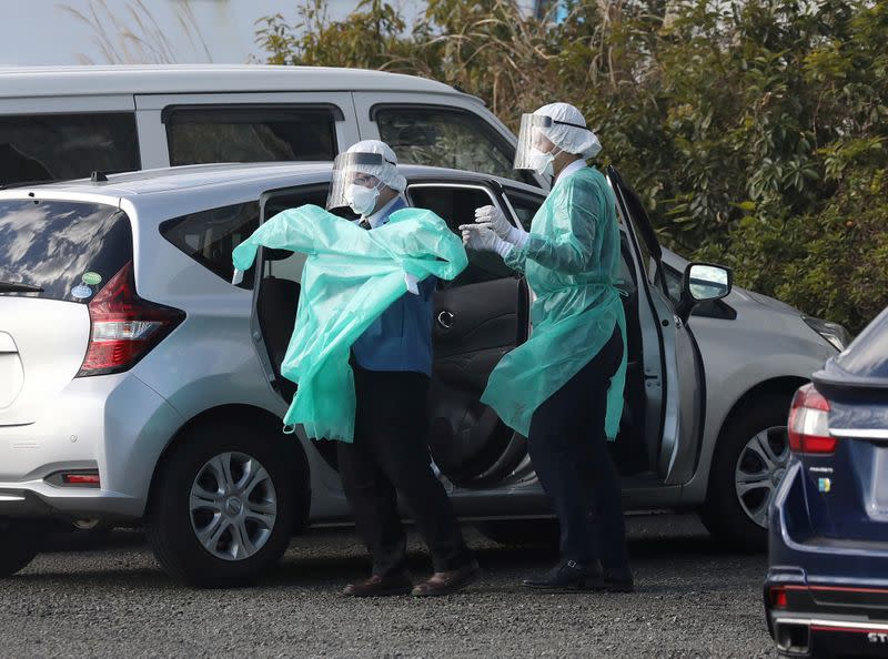 Health officials dressed in protective gear are seen near the cruise ship Diamond Princess at Daikoku Pier Cruise Terminal in Yokohama