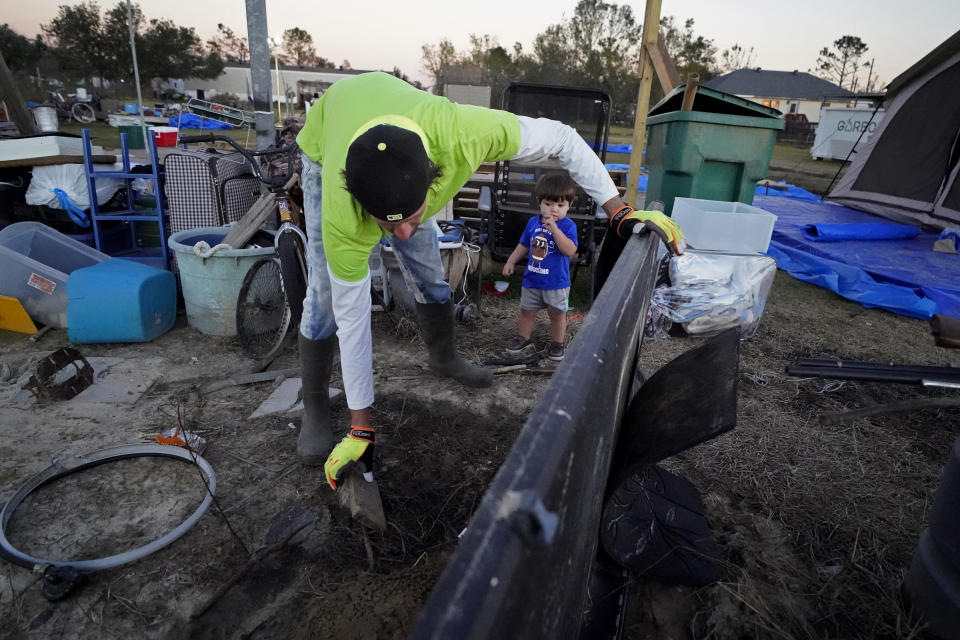 Ricky Trahan sorts debris on his property while his grandson Ricky Trahan, III stands nearby, after their home was destroyed by both Hurricane Laura and Hurricane Delta in Lake Charles, La., Friday, Dec. 4, 2020. The family is living in tents, with their son, his fiancee and their son Ricky III living in a loaned camper there. His sister's family's home is now gutted and they are living in a camper on the same property. (AP Photo/Gerald Herbert)