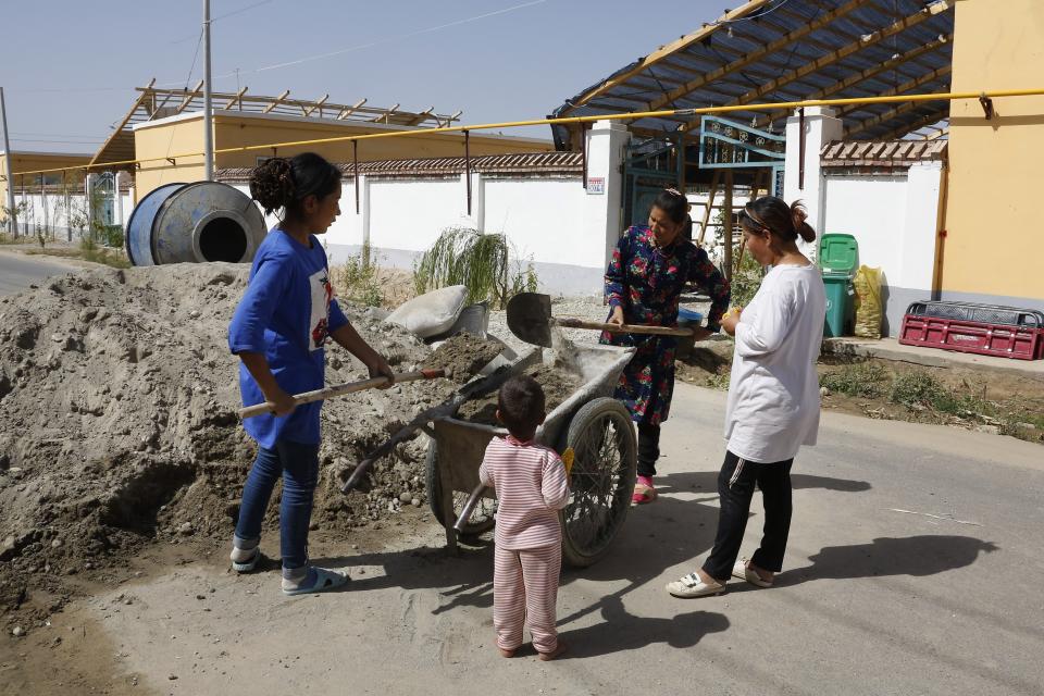 In this Sept. 21, 2018, photo, Uighur women use carts to transport cement for home renovations at the Unity New Village in Hotan, in western China's Xinjiang region. While thousands of Uighur Muslims across China’s Xinjiang region are forced into re-education camps, China’s fledgling vision for ethnic unity is taking shape in a village where Han Chinese work and live alongside Uighur minorities. (AP Photo/Andy Wong)