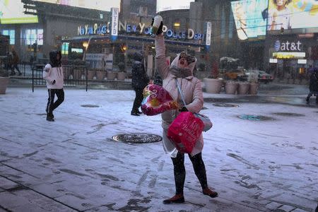 A woman twirls and dances in celebration as it begins to snow in Times Square in the Manhattan borough of New York, January 23, 2016. REUTERS/Carlo Allegri