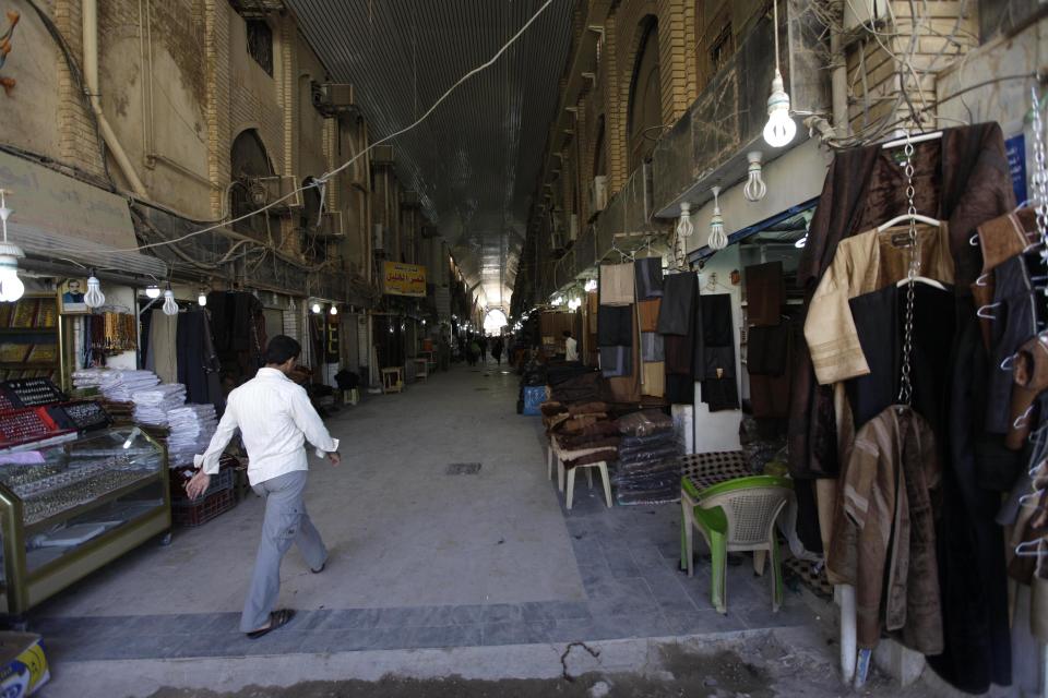 In this photo taken in Tuesday, Oct. 30, 2012, a man walks past empty shops in Najaf, Iraq The plunge in Iran's currency is proving bad for business in neighboring Iraq. Fewer Iranians are now able to afford visits to Shiite holy sites here and elsewhere in Iraq because each dollar or Iraqi dinar now costs roughly three times what it did as recently as last year. That has pushed the price of organized tours up sharply and made Iraqi merchants far less willing to accept rials as payment. (AP Photo/Khalid Mohammed)