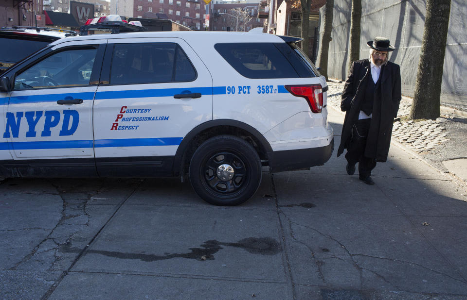 A Hasidic man walks past a police patrol car on Dec. 12 in the Williamsburg neighborhood of Brooklyn. Hasidic leaders have asked for a stronger police presence. (Photo: Andrew Lichtenstein/Getty Images)