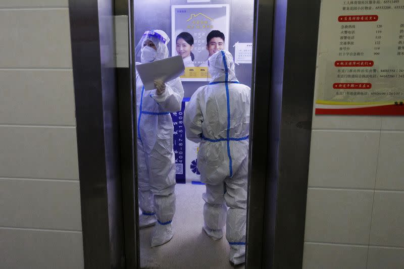 Pandemic prevention workers in protective suits stand in an elevator on their way to take a count of the residents in a building that went into lockdown as coronavirus disease (COVID-19) outbreaks continue in Beijing