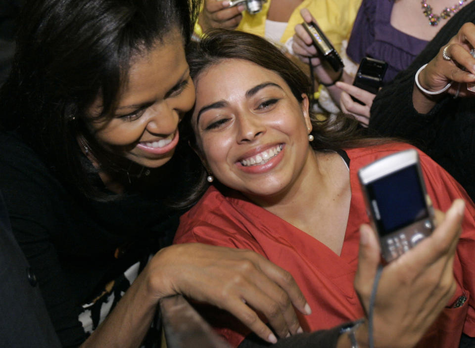 File - In this Friday, Oct. 24, 2008, file photo Michelle Obama, left, wife of Democratic presidential candidate Sen. Barack Obama, D-Ill., takes a picture with a supporter after speaking at a rally at Buchtel High School in Akron, Ohio. Selfie" the smartphone self-portrait has been declared word of the year for 2013 by Britain's Oxford University Press. (AP Photo/Tony Dejak, File)