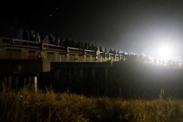 Dakota Access protesters stand their ground on the bridge between Oceti Sakowin Camp and County Road 134 in North Dakota on Nov. 20, 2016, while being sprayed with water cannons and tear gas — paintballs, rubber bullets and sound cannons were also used. The protesters built a fire to stay warm in 26-degree weather while also being soaked by police. (Photo: Cassi Alexandra for The Washington Post via Getty Images)