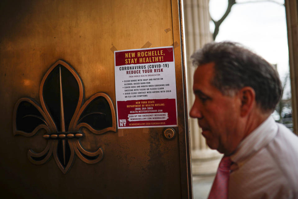 A sign providing instructions on how to reduce the risk of contracting or spreading COVID-19 is hung on the front door of New Rochelle City Hall, Tuesday, March 10, 2020, in New Rochelle, N.Y. State officials are shuttering schools and houses of worship for two weeks in part of the New York City suburb New Rochelle and sending the National Guard there to help respond to what appears to be the nation's biggest cluster of coronavirus cases. (AP Photo/John Minchillo)