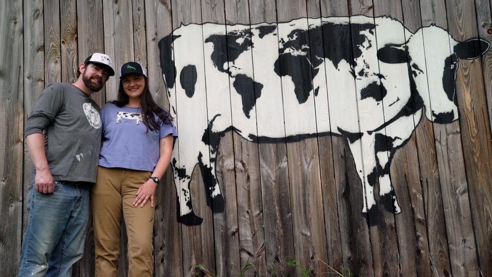 DJ Barry (left) and Jen Gordon (right) man a World Cow mural at the Marshfield Inn & Motel in Marshfield on May 23, 2023.