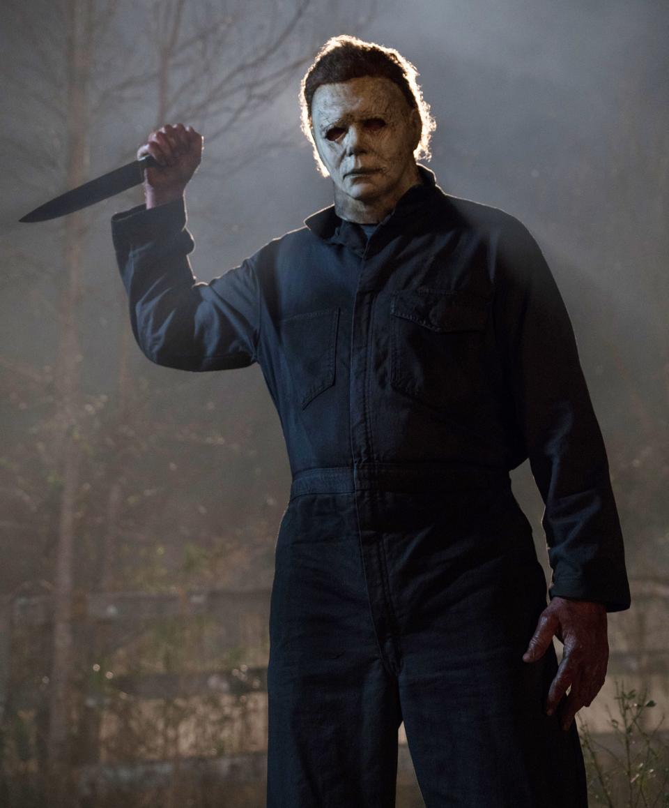 Michael Myers holding a knife, wearing a mask and dark coveralls, in a scene from "Halloween"