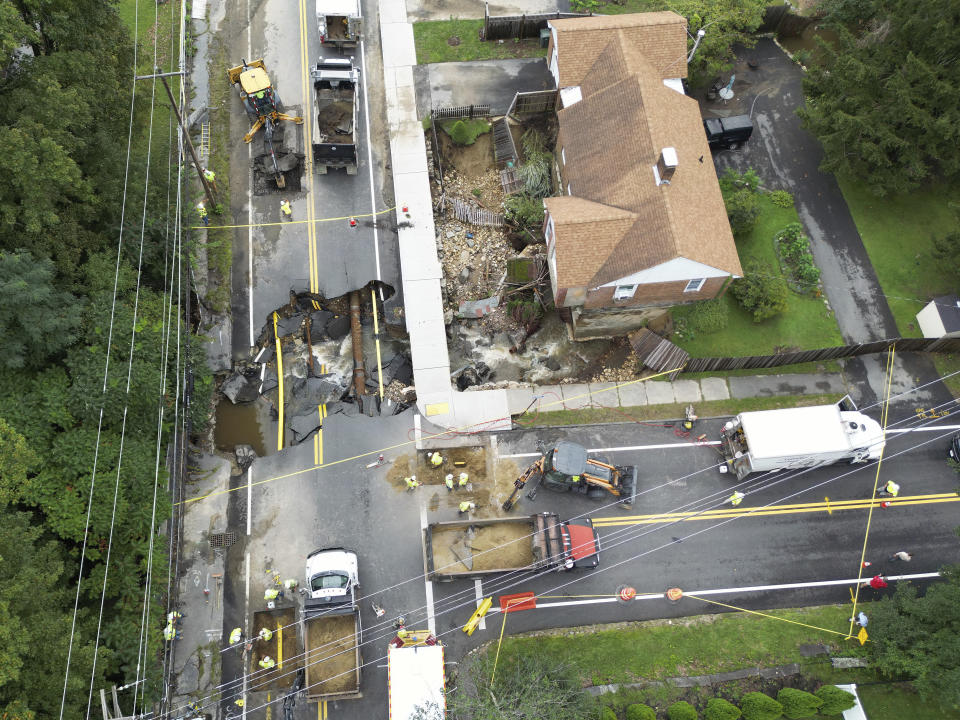 Crews work on a section of Pleasant Street in Leominster, Mass., which was washed out Tuesday, Sept. 12, 2023, after heavy rain fall in the town overnight. (AP Photo/Josh Reynolds)