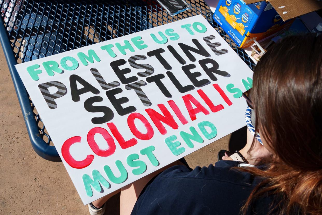 Kaland Kelly works on a sign that reads, "from the US to Palestine, settler colonialism must end," at a Students for Justice in Palestine arts and crafts, sign-making and education event at Tempe Beach Park on Oct. 8, 2023, in Tempe.