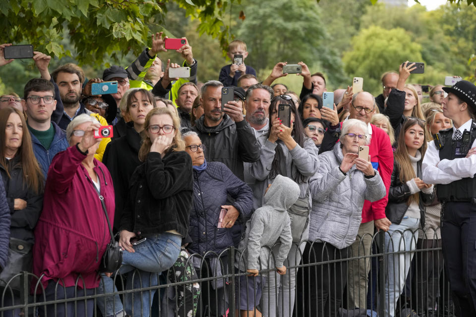 Mourners take photos as the coffin of Queen Elizabeth II is pulled on a gun carriage through the streets of London following her funeral service at Westminster Abbey, Monday Sept. 19, 2022.The Queen, who died aged 96 on Sept. 8, will be buried at Windsor alongside her late husband, Prince Philip, who died last year. (AP Photo/Kin Cheung,Pool)