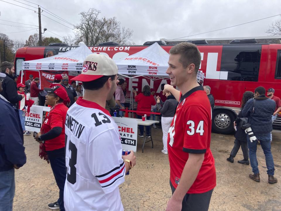 University of Georgia football fans Zach Jacobs, left, and Zach Adams, right, talk after they met Republican U.S. Senate nominee Herschel Walker in Atlanta, Saturday, Dec. 3, 2022. The 23-year-old Georgia fans consider Walker, a former Bulldog football star, one of their sports heroes but also support his bid to unseat Democratic Sen. Raphael Warnock in a Tuesday runoff. Sports and college loyalties have figured prominently in Georgia's Senate race and other midterm contests in the Deep South battleground state. (AP Photo/Bill Barrow)