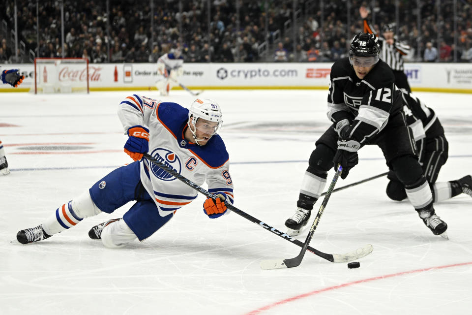 Edmonton Oilers center Connor McDavid, left, falls as he tries to pass the puck while under pressure from Los Angeles Kings left wing Trevor Moore during the second period of an NHL hockey game Tuesday, April 4, 2023, in Los Angeles. (AP Photo/Mark J. Terrill)