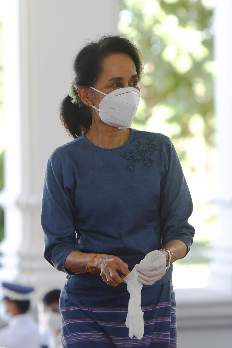 Myanmar's leader Aung San Suu Kyi puts on gloves before she makes an early voting for upcoming Nov. 8 general election at Union Election Commission office in Naypyitaw, Myanmar Thursday, Oct. 29, 2020. (AP Photo/Aung Shine Oo)