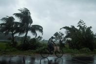 A man rides a bicycle under the rain ahead of the expected landfall of cyclone Amphan in Midnapore, West Bengal, on May 20, 2020. (Photo by Dibyangshu SARKAR / AFP)