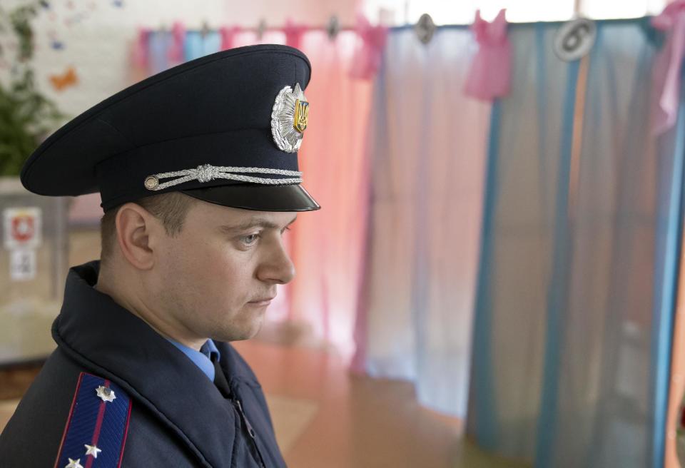 A Ukrainian policeman supervises activity in a voting station in Perevalne, Ukraine, Sunday, March 16, 2014. Residents of Ukraine's Crimea region are voting in a contentious referendum on whether to split off and seek annexation by Russia. (AP Photo/Vadim Ghirda)