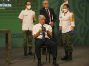 Mexican President Andres Manuel Lopez Obrador shows his vaccination certificate after getting a shot of the AstraZeneca vaccine for COVID-19 during his daily, morning news conference at the presidential palace in Mexico City, Tuesday, April 20, 2021. (AP Photo/Fernando Llano)