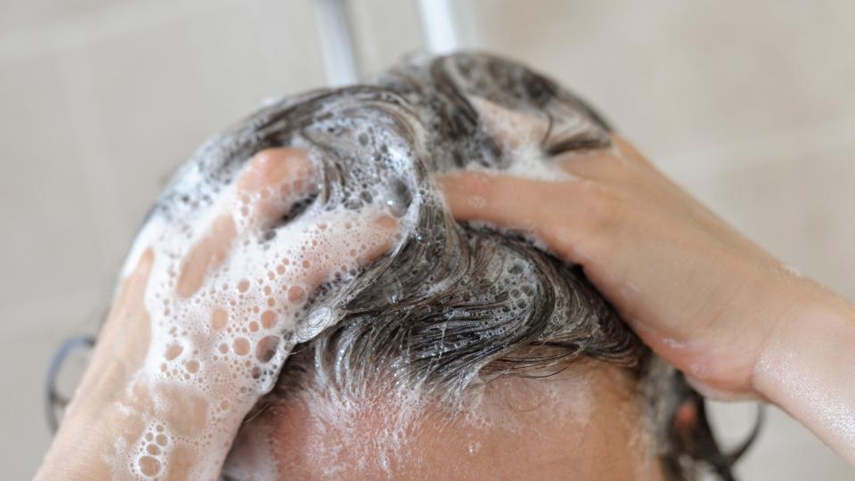 A close up of a woman shampooing her hair whilst in the shower