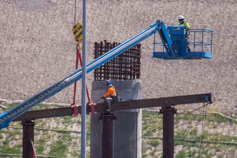 Work crews continue to work on the construction of a freeway overpass in San Diego