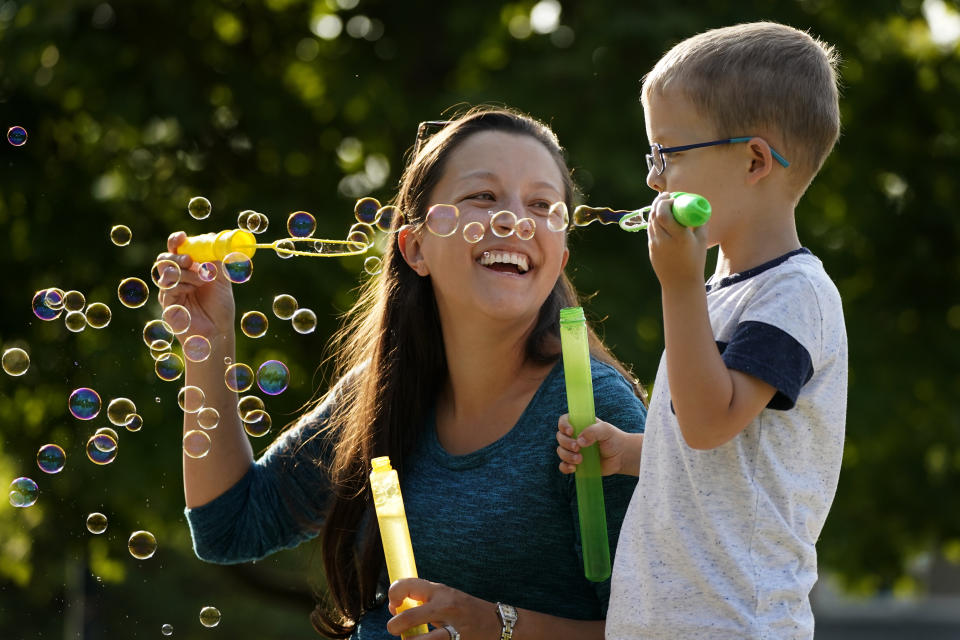 Claire Reagan plays with her son Evan, 5, Monday, Sept. 21, 2020, outside her home in Olathe, Kan. Reagan is keeping her son from starting kindergarten and her daughter Abbie, 3, from preschool due to concerns about the coronavirus pandemic. (AP Photo/Charlie Riedel)