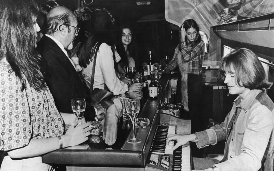 Led Zeppelin's John Paul Jones playing the organ behind the bar on board the band's plane The Starship - Hulton Archive 