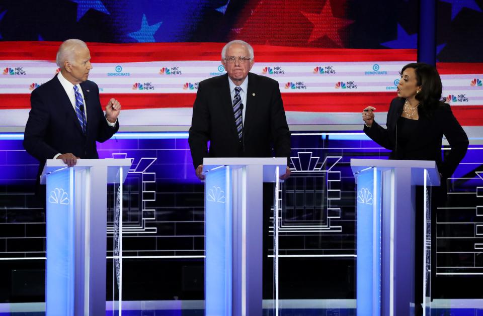 Sen. Kamala Harris, D-Calif., and former Vice President Joe Biden speak as Sen. Bernie Sanders, I-Vt., looks on during the second night of the first Democratic presidential debate on June 27, 2019 in Miami, Florida