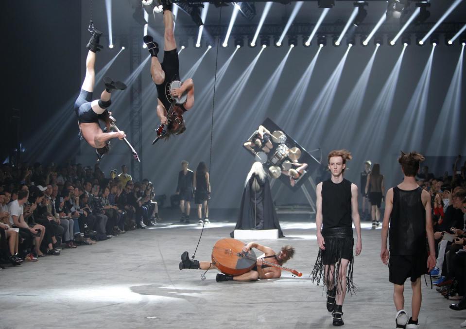 Models wear creations by fashion designer Rick Owens as part of his men's fashion Spring-Summer 2014 collection, presented Thursday, June 27, 2013 in Paris, as Estonian metal/punk band Winny Puhh perform live, suspended by their feet . (AP Photo/Francois Mori)