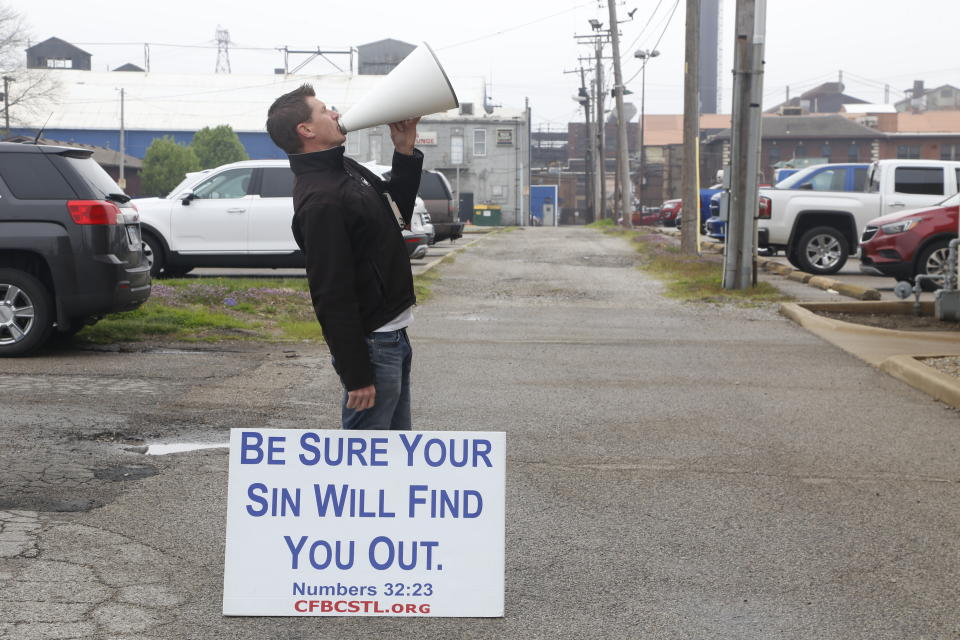 A pastor uses a megaphone to ask women not to get abortions on Tuesday, April 12, 2022, at the Hope Clinic for Women in Granite City, Ill. The pastor, whose church is across the state line in the St. Louis area, declined to give his name but said he stands outside the clinic and does this often. More women from Missouri and states much farther away are coming to Illinois for abortions, as more states restrict that kind of care. (AP Photo/Martha Irvine)