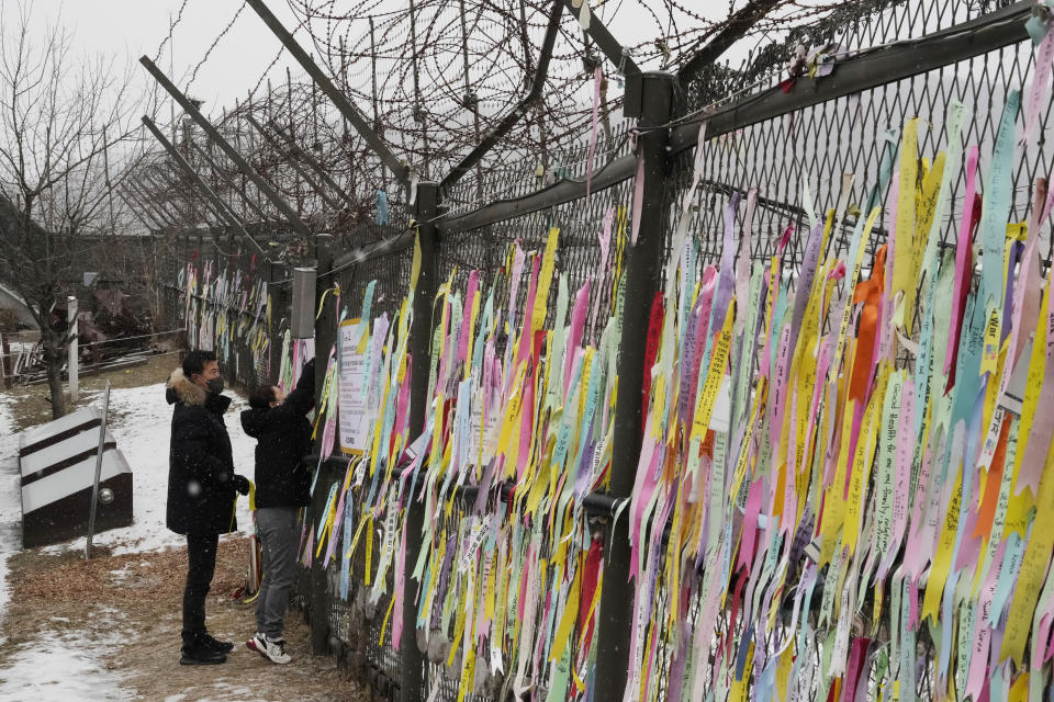 A woman hangs a ribbon wishing for the reunification of the two Koreas on a fence as she visit the Imjingak Pavilion, near the border with the North, to celebrate the Lunar New Year in Paju, South Korea, Sunday, Jan. 22, 2023. (AP Photo/Ahn Young-joon)