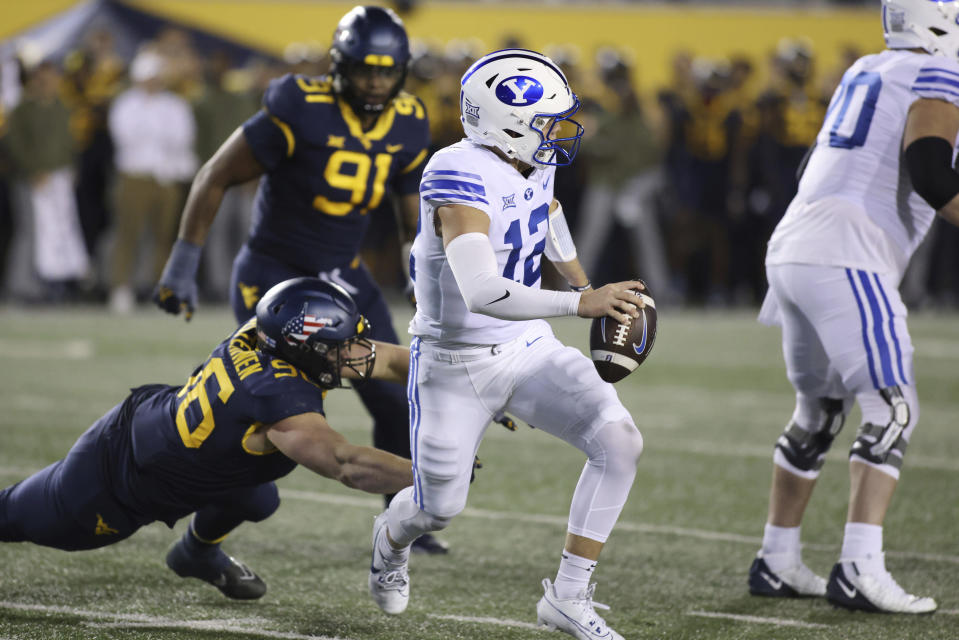 BYU quarterback Jake Retzlaff (12) is rushed out by West Virginia's Edward Vesterinen (96) during the first half of an NCAA college football game on Saturday, Nov. 4, 2023, in Morgantown, W.Va. (AP Photo/Chris Jackson)