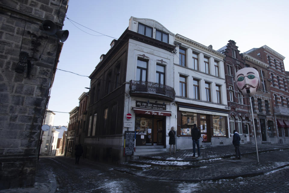 People wearing protective face masks wait in a line outside a specialty shop in the Grand Place in Binche, Belgium, Thursday, Feb. 11, 2021. In normal life, the small town of Binche in southern Belgium would be bursting with excitement for the carnival festivities that have been labeled a 'Masterpiece of the Oral and Intangible Heritage of Humanity' by UNESCO, but in 2021 the COVID-19 regulations have forced the carnival to be cancelled.(AP Photo/Virginia Mayo)