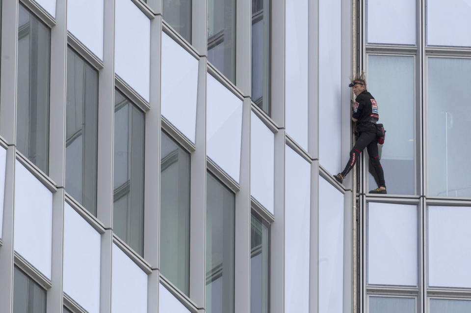 People look out of their windows as French urban climber Alain Robert, known as 'Spiderman', climbs up the 231 meter high (758 feet) First Tower, the tallest skyscraper in France, in the La Defense business district in Courbevoie, outside Paris, Thursday, May 10, 2012. (AP Photo/Michel Euler)