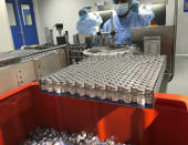 Production personnel perform the labeling operation of inspected vaccine vials inside the Incepta plant on the outskirts of Dhaka in Bangladesh Saturday Feb. 13, 2021. (AP Photo/Al-emrun Garjon)