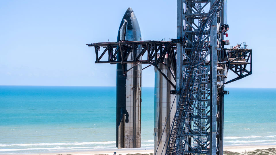 a silver rocket towers above a turquoise ocean in the background.