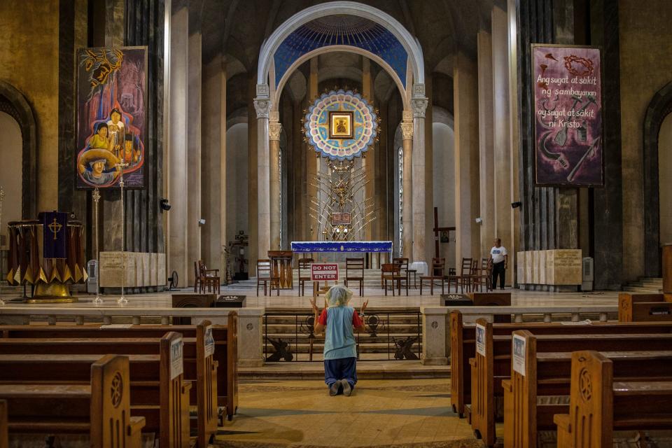 A woman prays on her knees in the aisle of an empty church as authorities ban religious gatherings amid the threat of the coronavirus on March 22, 2020 in Manila, Philippines.