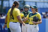 Australia's Kaia Parnaby, right, hands the ball to teammate Tarni Stepto during the softball game between Japan and Australia at the 2020 Summer Olympics, Wednesday, July 21, 2021, in Fukushima, Japan. (AP Photo/Jae C. Hong)