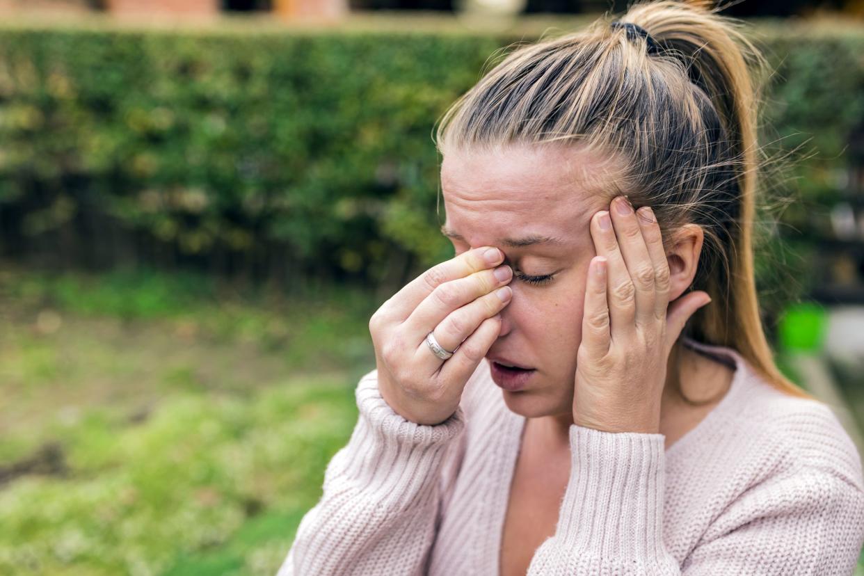 woman holding face with expression of severe sinus pain