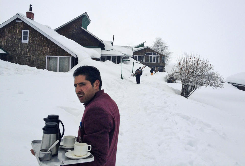 In this photo taken Tuesday, Feb. 26, 2013, a hotel worker stands with a tray of tea at a hotel in Gulmarg, Kashmir. Gulmarg, a ski resort nestled in the Himalayan mountains in Indian-held Kashmir is one of the most militarized places on earth. (AP Photo/Kevin Frayer)