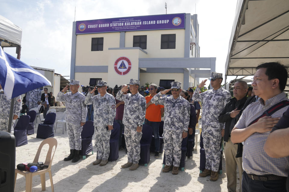 Coast guard officers salute during ceremonies for the inauguration of their new building at the Philippine-occupied Thitu island, locally called Pag-asa island, on Friday, Dec. 1, 2023, at the disputed South China Sea. The Philippine coast guard inaugurated a new monitoring base Friday on a remote island occupied by Filipino forces in the disputed South China Sea as Manila ramps up efforts to counter China's increasingly aggressive actions in the strategic waterway. (AP Photo/Aaron Favila)