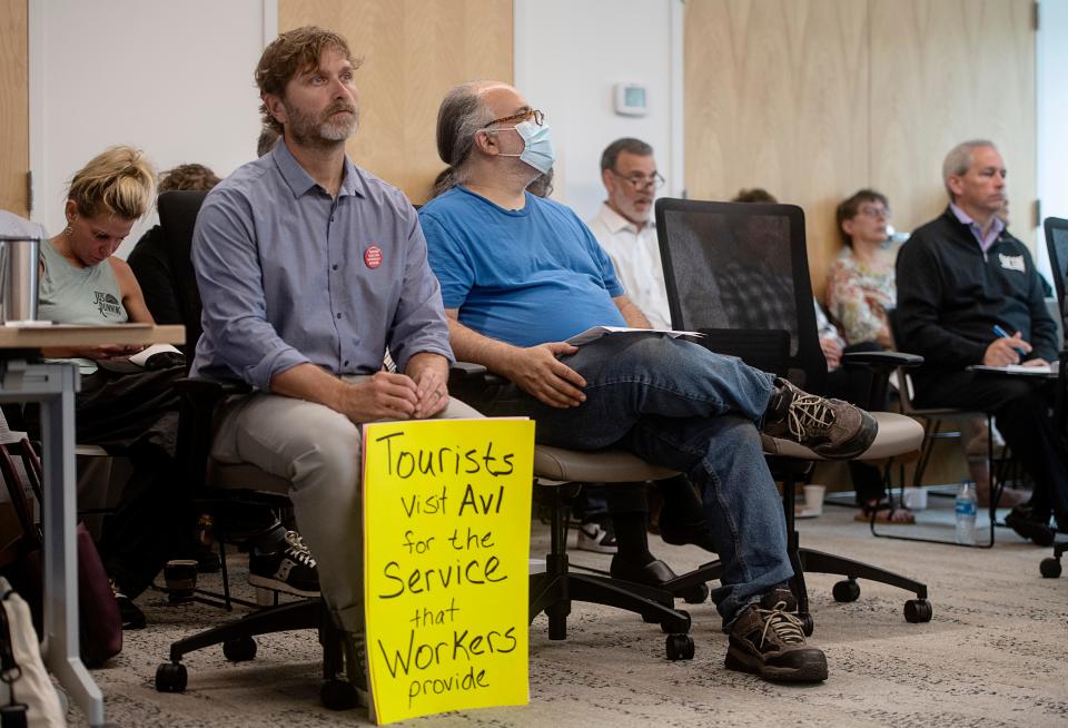 Ben Williamson, left, of Buncombe Decides holds a sign and listens during the TDA meeting May 31, 2023.