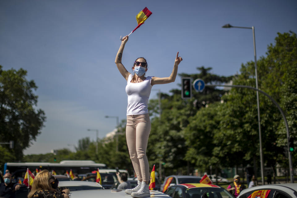 A woman waves a Spanish flag during a drive-in protest organised by Spain's far-right party Vox against the Spanish government's handling of the nation's coronavirus outbreak in Madrid, Spain Saturday, May 23, 2020. (AP Photo/Manu Fernandez)