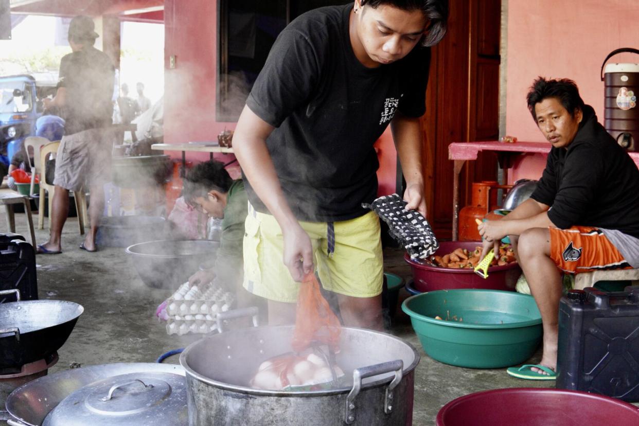 Volunteers boiling eggs and peeling carrots.