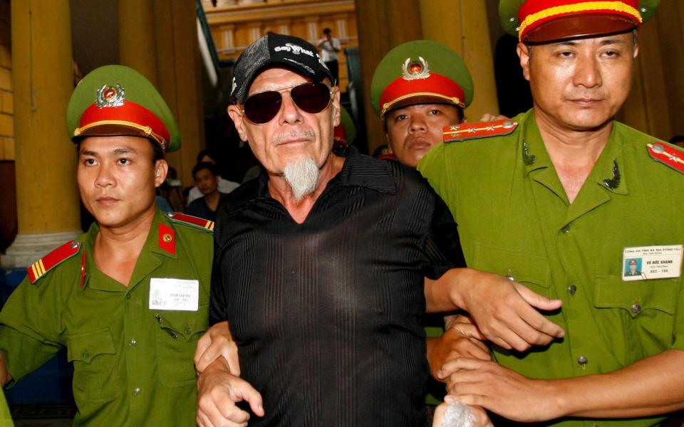 Fallen British glam rock star Gary Glitter (C) is escorted by police out of a courtroom after losing his appeal hearing in a child molestation case in Ho Chi Minh City, Vietnam - Credit: EPA