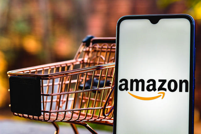 Amazon logo on phone next to shopping cart