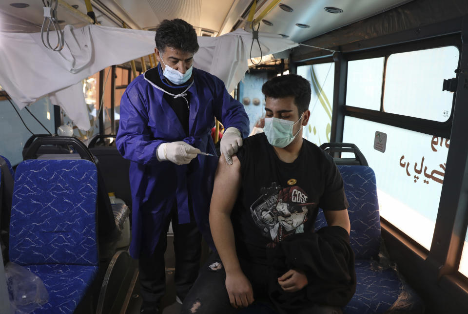 A man receives a COVID-19 vaccine at a mobile vaccine clinic bus at the Grand Bazaar of Tehran, Iran, Saturday, Jan. 22, 2022. After successive virus waves pummeled the country for nearly two years, belated mass vaccination under a new, hard-line president has, for a brief moment, left the stricken nation with a feeling of apparent safety. (AP Photo/Vahid Salemi)