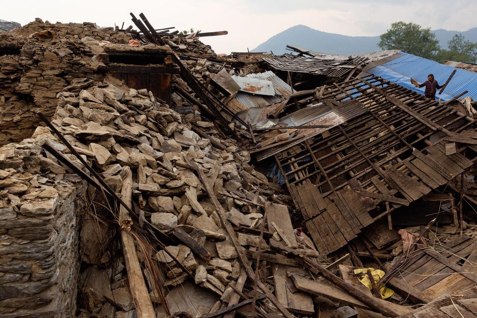 Nepal earthquake. Barpak, the epicenter of the earthquake. Funeral of Pur Bahadur Gurung, 26, who had just been dug out of the rubble. Saainli Gurung, his mother weeping. Scenes of villagers salvaging building materials and personal possessions. Dhan Raj Ghale, 30, dressed in mourning garb after the death of his wite, salvaging buildings materials and possessions from his house. by James Nachtwey